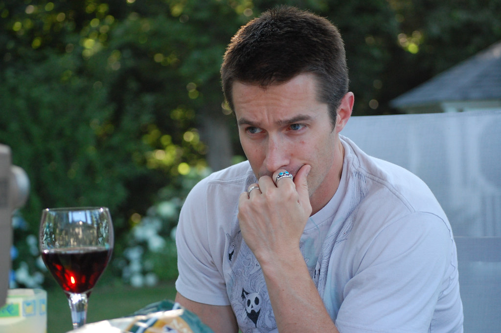 man looking at wine in glass
